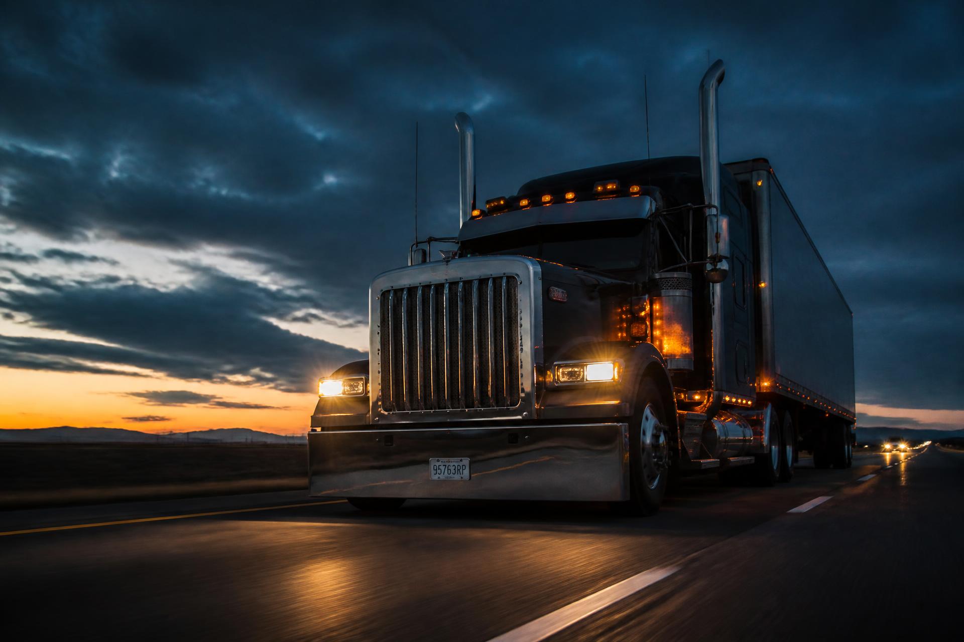 Semi truck hauling freight on an open highway at dusk